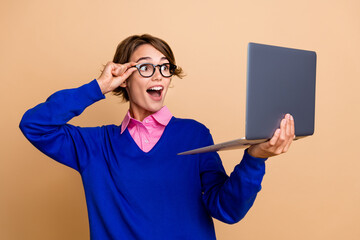 Portrait of impressed cheerful trader girl arm touch eyewear look laptop screen isolated on beige...