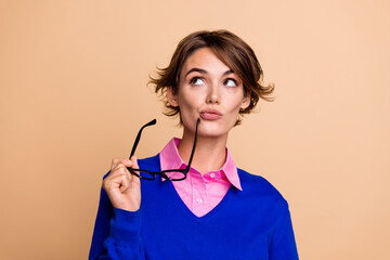 Portrait of intelligent creative girl hold eyeglasses look empty space ponder isolated on beige...