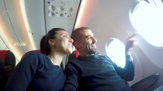 Happy couple on a plane enjoying honeymoon trip together