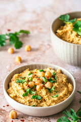 Hummus, chickpea puree with coriander in a bowl on light background, vertical