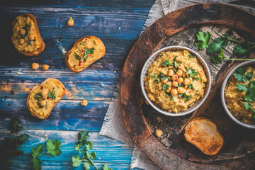 Hummus, chickpea puree in a bowl and on toasted bread slices