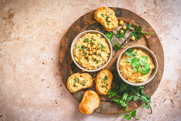 Hummus, chickpea puree in a bowl and on toasted bread slices