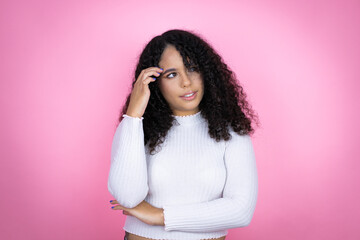 African american woman wearing casual sweater over pink background confuse and wonder about question. Uncertain with doubt, thinking with hand on head - obrazy, fototapety, plakaty