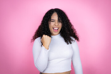 African american woman wearing casual sweater over pink background angry and mad raising fist...