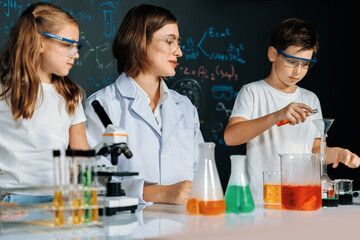 Teacher in support and watch student in laboratory they wear safety glasses, stand and experiment about science of chemistry in STEM class. Student funny do experiment with liquid in tube. Erudition.