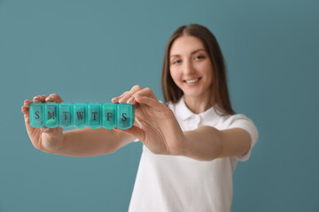 Beautiful woman with container of vitamin supplements on blue background, closeup