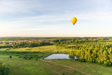 yellow hot air balloon in the sky over the lake and forest