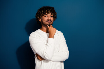 Fototapeta na wymiar Portrait of young intelligent business man wearing white jumper touch chin likes his profession isolated on dark blue color background