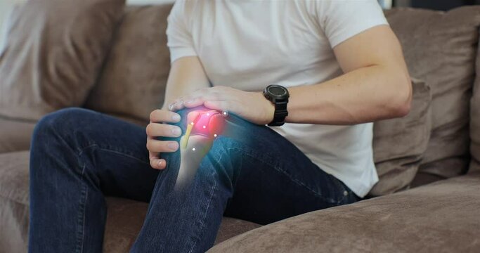 3d augmented reality animation joint and knee pain. Close up of young man touching his knee feel pain and doing massage sitting on couch at home. People health care problem.