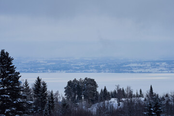 Fototapeta premium A frozen Lake Mjosa with the Grythenholm-plateau seen from Kronborgsetergrenda, Toten, Norway, a morning of March.