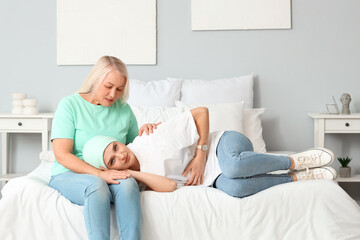 Young woman after chemotherapy with her mother in bedroom. Stomach cancer concept