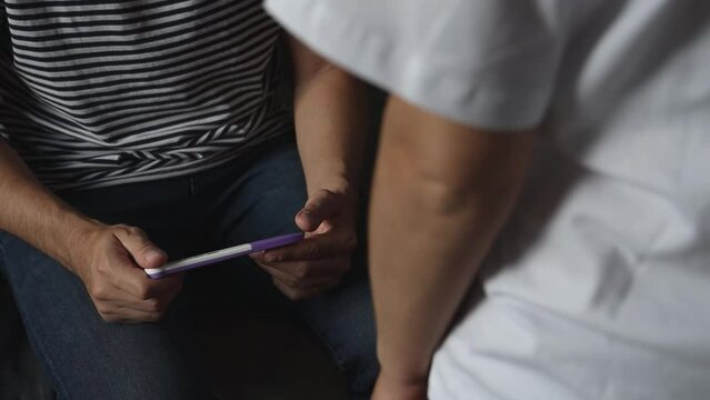 woman showing positive pregnancy test to man.