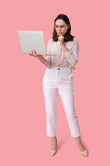 Pondering businesswoman with laptop on pink background