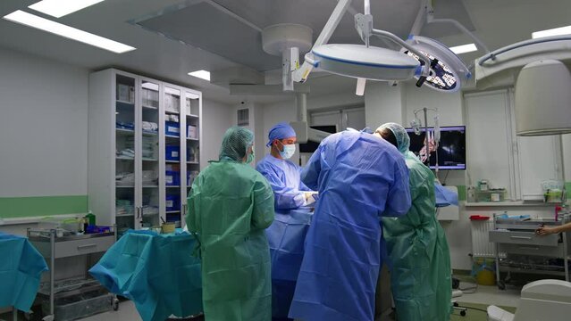 Two surgeons, assistant and scrub nurse surrounding the operational table. Surgical team carrying out the trauma surgery.