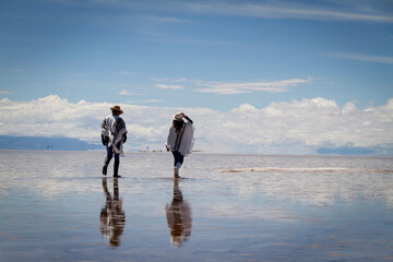 Pareja alegre caminado sobre agua en salar de Uyuni Bolivia.