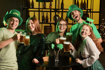 Group of young friends with beer celebrating St. Patrick's Day in pub at night