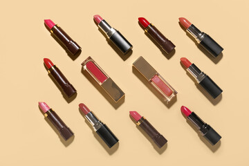 Different lipsticks and lip glosses on light yellow background