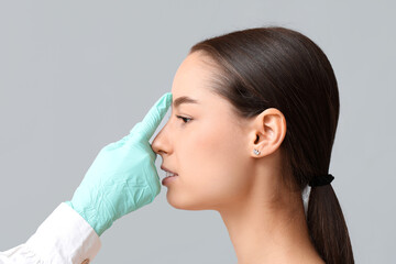 Doctor checking woman's nose before plastic surgery on white background