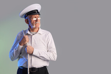 Mature sailor with rope on grey background