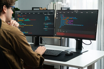 IT developer working online software development on pc monitors at modern home office on coding application screens, creating updated latest program firmware information version concept. Gusher. - obrazy, fototapety, plakaty