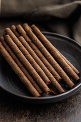 Chocolate Wafer Rolls on plate on dark table.