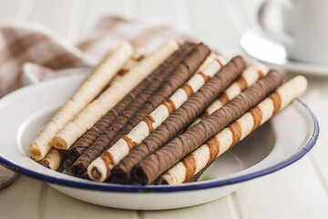 Assorted Chocolate and Vanilla Cream Filled Wafer rolls on plate on white table.