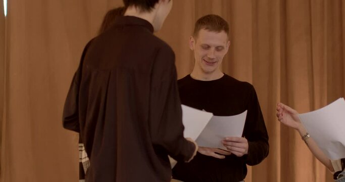 Students of the theater discuss a comedic play, laughing together. Humor and camaraderie fill the room as they share in the enjoyment of the comedic elements of the performance.