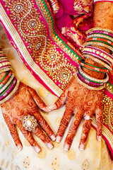 Fototapeta premium Indian bride hands on sari with henna tattoo bangles and diamond wedding ring