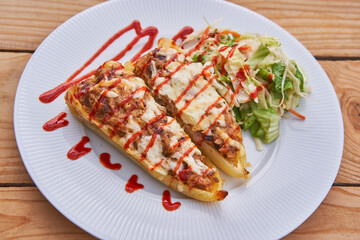 East european or balkan style stuffed sweet white pepper with minced pork meat, rice herbs and cheese and sparkled by red hot chilly sauce served on the white porcelain plate and wooden table isolated