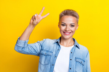 Photo portrait of pretty young girl show v-sign shopping promo wear trendy jeans outfit isolated on yellow color background