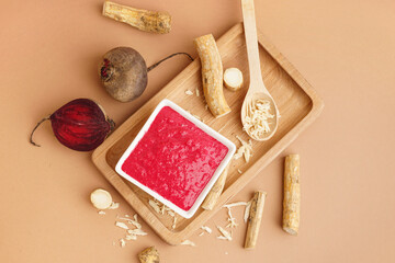 Horseradish sauce with beet in bowl  and pieces of beet on beige background. Top view