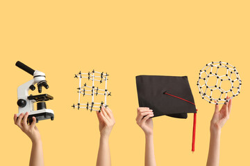 Female hands holding molecular models with microscope and graduation hat on yellow background....