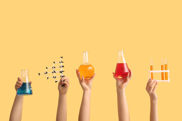 Female hands holding filled flasks with test tubes and molecular model on yellow background....