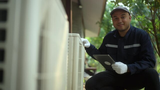 Air conditioner service outdoor checking fix repair with tablet. Air conditioner cleaning technician He opened the front cover and took out the filters and washed it. He in uniform wearing rubber.