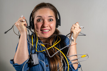 Mujer sosteniendo un montón de cables en expresión de problemas con la tecnología. Dificultades...