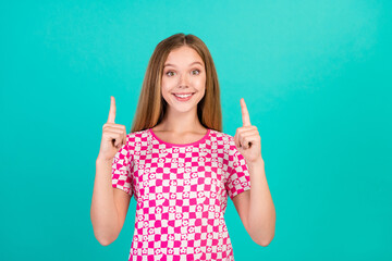 Photo portrait of lovely teen lady point up empty space promo dressed stylish pink print garment isolated on aquamarine color background