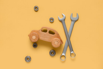 Wrenches, nuts and toy car on yellow background. Mechanic concept