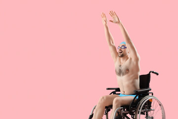 Male swimmer in wheelchair on pink background