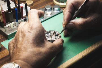 The hands of a watchmaker repairing a watch.