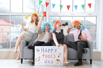 Business people with poster celebrating April Fools' Day on sofa at office party