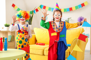 Obraz na płótnie Canvas Funny little children in clown costumes with flags at home. April Fools' Day celebration