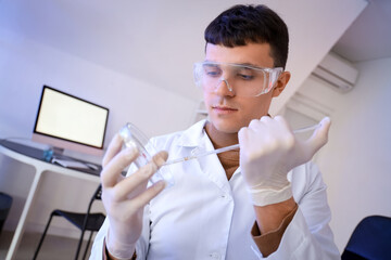 Male chemist working with Petri dish in laboratory, closeup