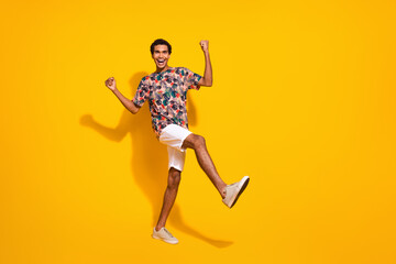 Full length body photo of successful young man in stylish summer apparel raised fists up win tournament isolated on yellow color background