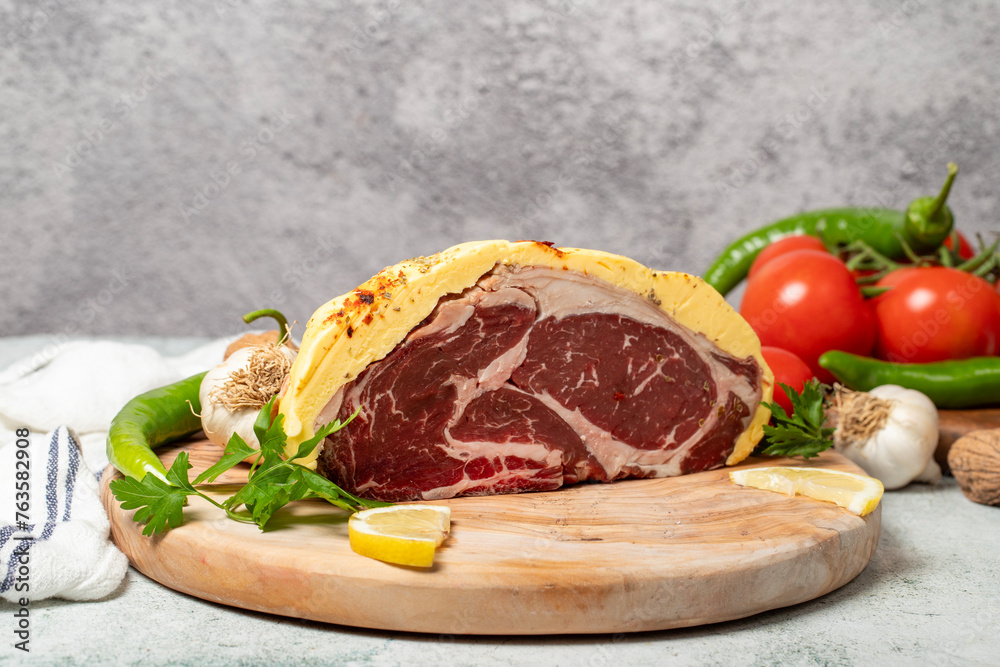 Wall mural Buttered ribeye. Raw ribeye surrounded by butter on wood serving board. Close up