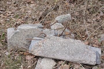 one old gray broken concrete pillar lies in the dry grass on the street