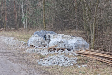 gray paving slabs in a heap on a pallet standing on the ground in the street