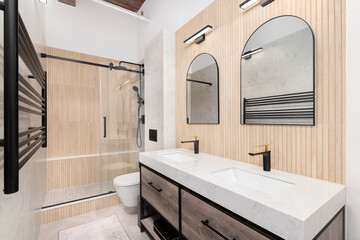 A bathroom with a wood slat accent wall, a marble slab countertop on a black and wood cabinet, and...