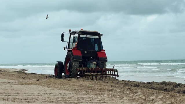 Varadero, December - 2023. Tractor on the beach of the Atlantic Ocean. A tractor cleans the sand on a Cuban beach. A tractor cleans the beach sand from algae. Cleaning the coast at the resort. 4К