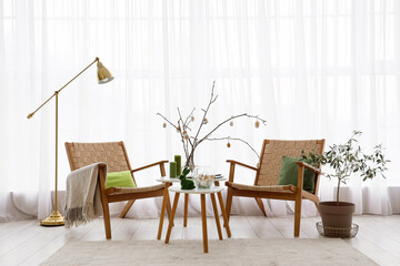 Interior of light room with armchairs, tree branches and Easter eggs - obrazy, fototapety, plakaty