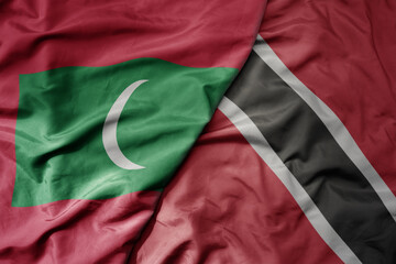 big waving national colorful flag of trinidad and tobago and national flag of maldives .